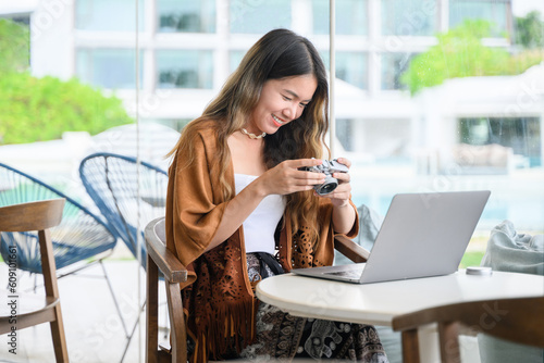 Fotografia, Obraz Asian woman using digital camera and laptop at coffee shop