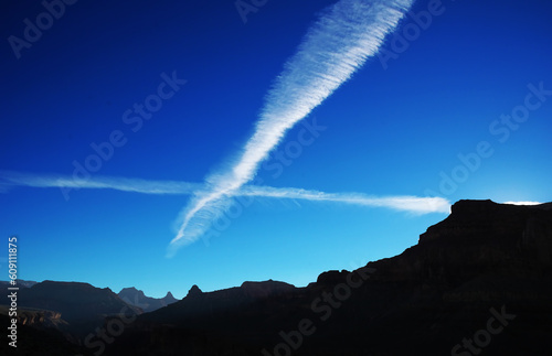 Jet streams in evening sky above the grand canyon, with canyon walls in silhouette. Lots of copy space.