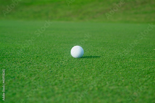 Golf ball with shadow on flat green
