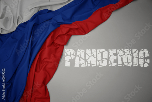 waving colorful national flag of russia on a gray background with broken text pandemic. concept.