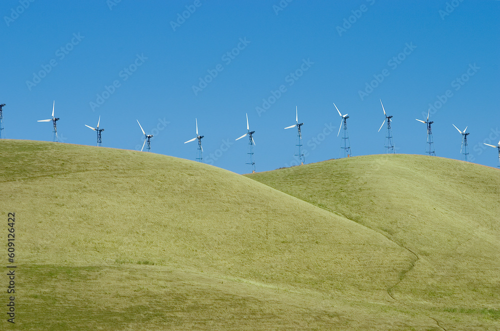Fototapeta premium A line of windmills on rolling hills in California.