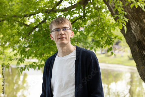 Portrait Of Tall Blond 40 Yo Man In Eyesight Glasses, Smiling Looking At Camera, Green Tree And Lake On Background. Horizontal Plane