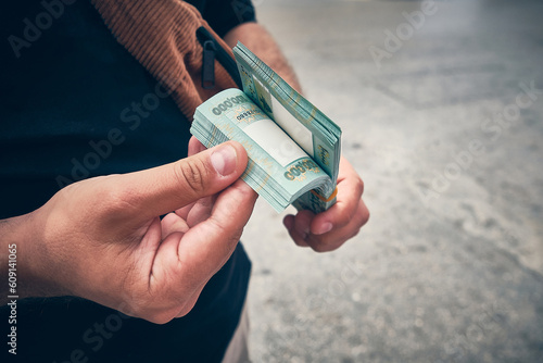 Man holds stack of Lebanese liras equivalent to one hundred dollars. Hyperinflation in Lebanon. Devaluation of Lebanese currency. Hands of man counting Lebanese pounds photo