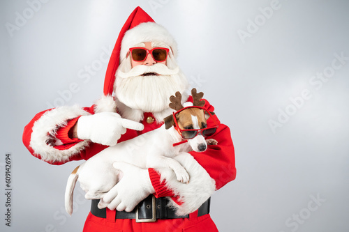 Obraz na plátne Portrait of santa claus in sunglasses and dog jack russell terrier in rudolf reindeer ears on a white background