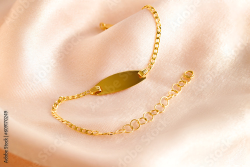 Golden bracelet with name plate on a pink background. Romantic decorations. Сoncept for Valentine's Day