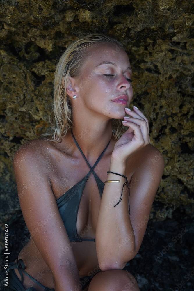 Attractive blonde woman in swimsuit on rocky beach. Attractive blonde woman in swimsuit on rocky beach.