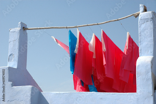 Photography Blue and pink textiles hanging at a blue stone building in India.