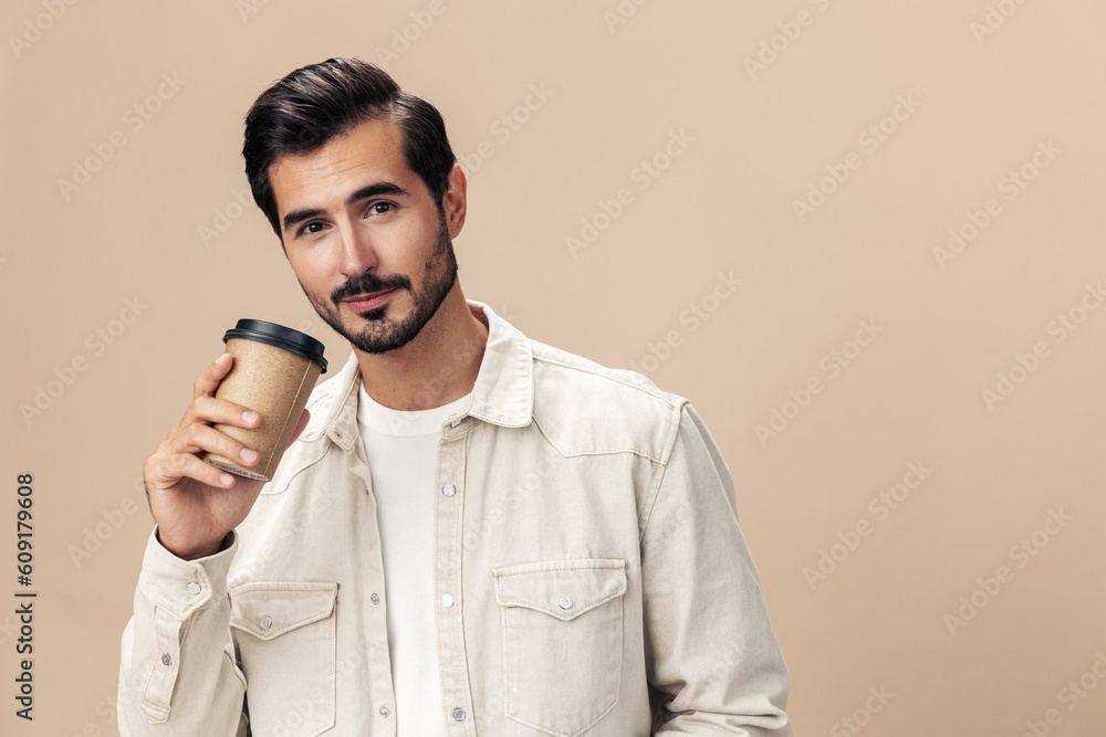 Portrait of a stylish man with a glass of coffee with himself mockup on a beige background in a white t-shirt, fashionable clothing style, space space Portrait of a stylish man with a glass of coffee with himself mockup on a beige background in a white t-shirt, fashionable clothing style, space space