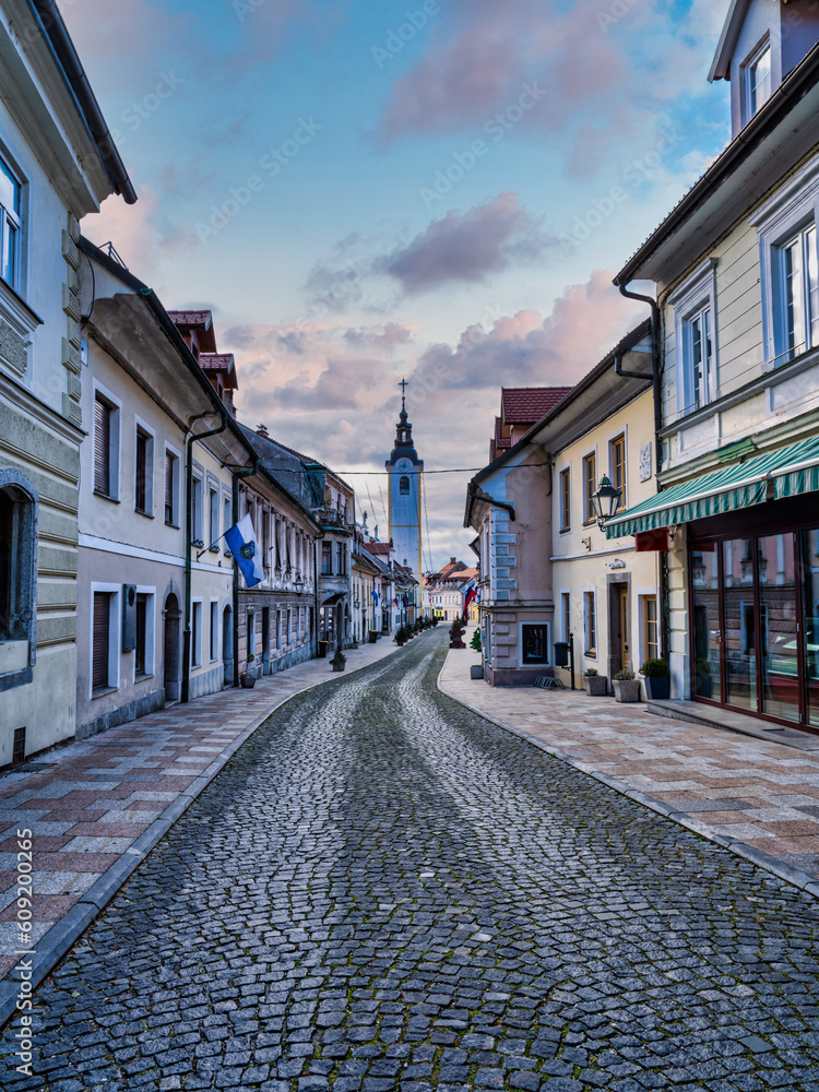 Vertical shot of the Cobblestone Sutna street old houses and shops with colorful cloud sky, Kamnik, Slovenia