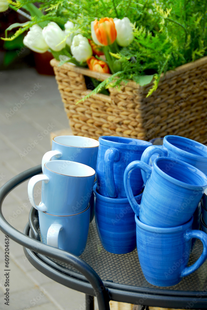 Blue cups and flower basket on a metal side table