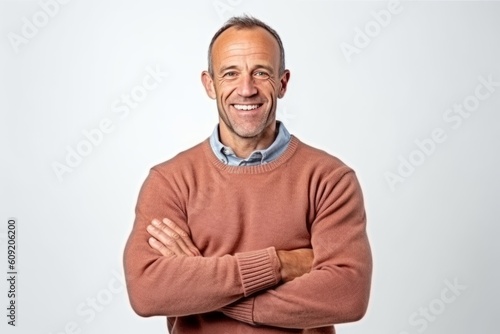 Portrait of happy mature man with arms crossed standing over white background