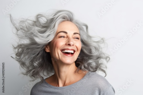 Portrait of a happy mature woman with long gray hair on a gray background