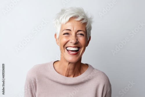 Portrait of a happy senior woman laughing while standing against white background