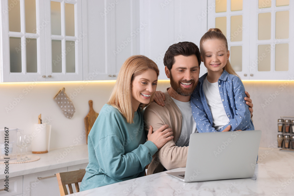 Happy family with laptop at white table indoors. Space for text Happy family with laptop at white table indoors. Space for text