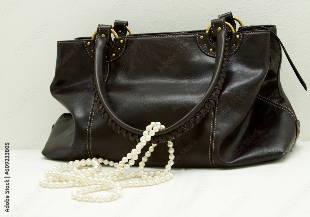 Naklejka premium Brown leather bag with white pearls on white background.