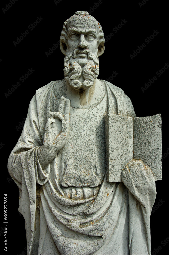 An ancient stone statue on the island of Torcello, in Venice, Italy, holding open a book and making the sign of a blessing.