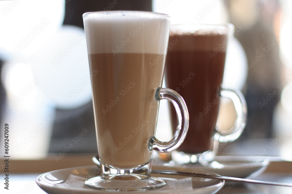Cafe Latte in a glass with hot chocolate in background Cafe Latte in a glass with hot chocolate in background