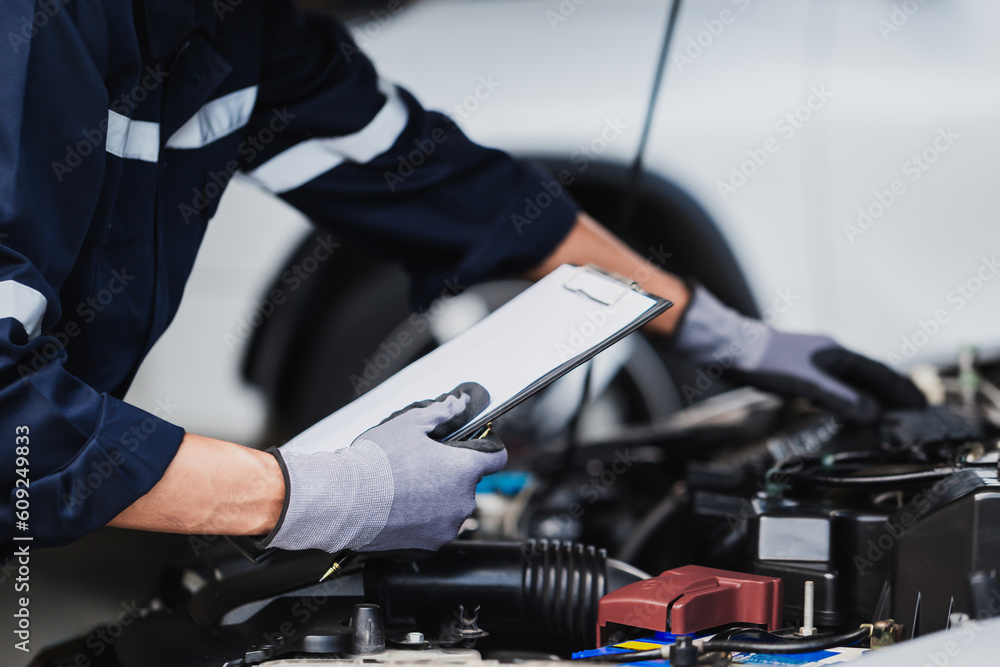 Professional mechanic working on the engine of the car in the garage. Car repair service. Professional mechanic working on the engine of the car in the garage. Car repair service.