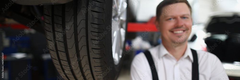 Φωτογραφία Smiling repairman man in auto repair shop near car lift
