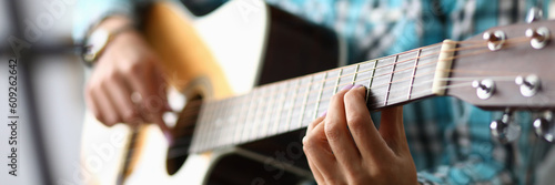 Woman hands playing guitar closeup. Learning to play acoustic guitar concept