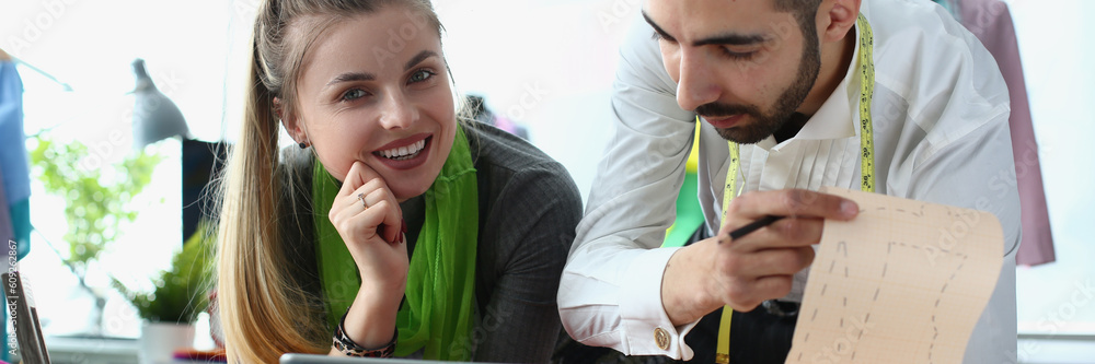 Business woman is using tablet talking to fashion stylist. Collaborates to create a stylish clothing collection Business woman is using tablet talking to fashion stylist. Collaborates to create a stylish clothing collection