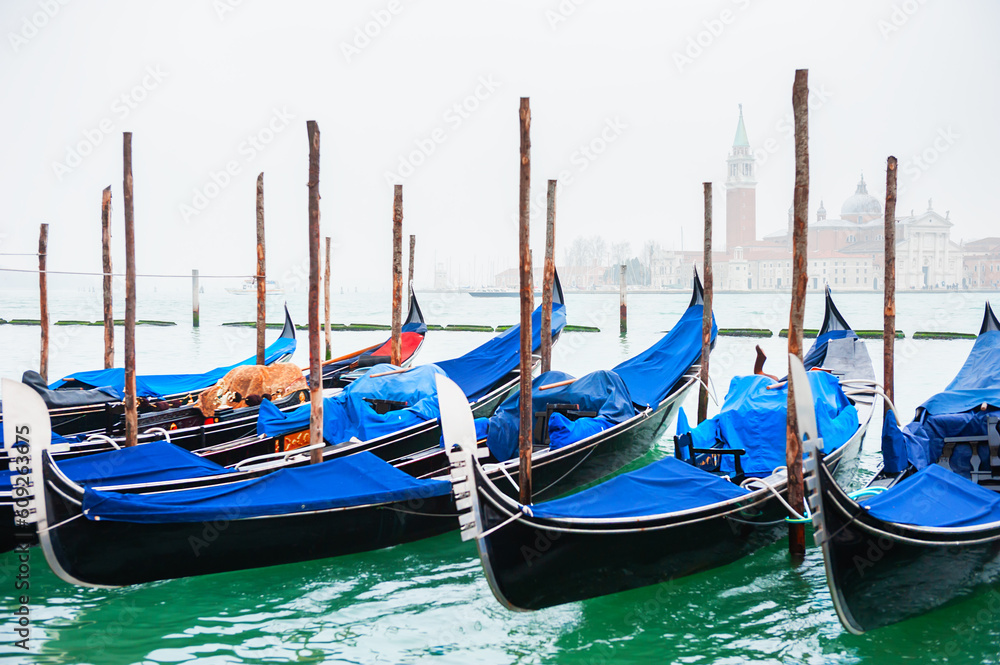 Gondolas on the Grand canal at foggy sunrise in Venice, Italy.