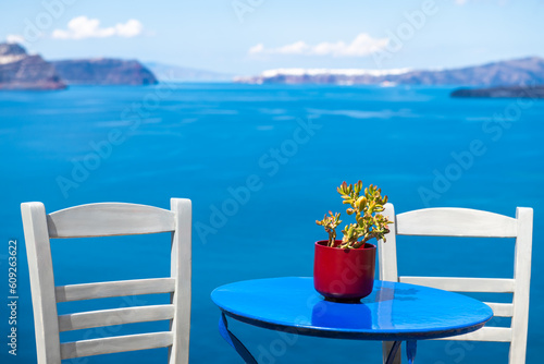 Santorini island  Greece. Two white chairs with blue table on the terrace with sea view.