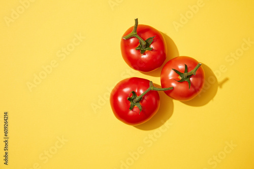 Three fresh tomatoes decorated on a light yellow background. Tomato (Solanum lycopersicum) is packed with vitamins and nutrients that are so advantageous for the skin