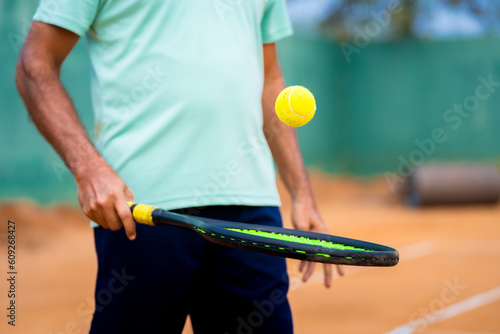 Close up shot of indian senior man playing or practising tennis at court - concept of training, healthy lifestyle and morning routine