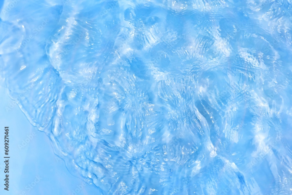 Obraz premium Blue water with ripples on the surface. Defocus blurred transparent blue colored clear calm water surface texture with splashes and bubbles. Water waves with shining pattern texture background.