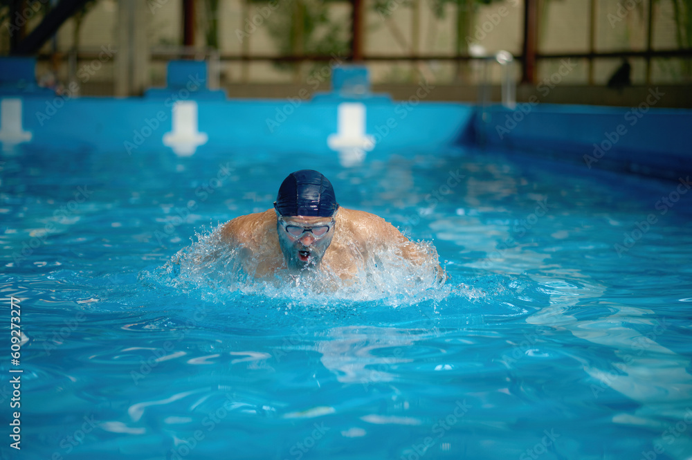 Senior man swimming fast in pool engaged in freestyle training
