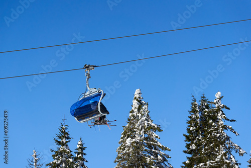 Chairlift of ropeway against blue sky. Cable car transports winter ski and snowboard riders. Ropeway. Germany, Black forest, Feldberg.