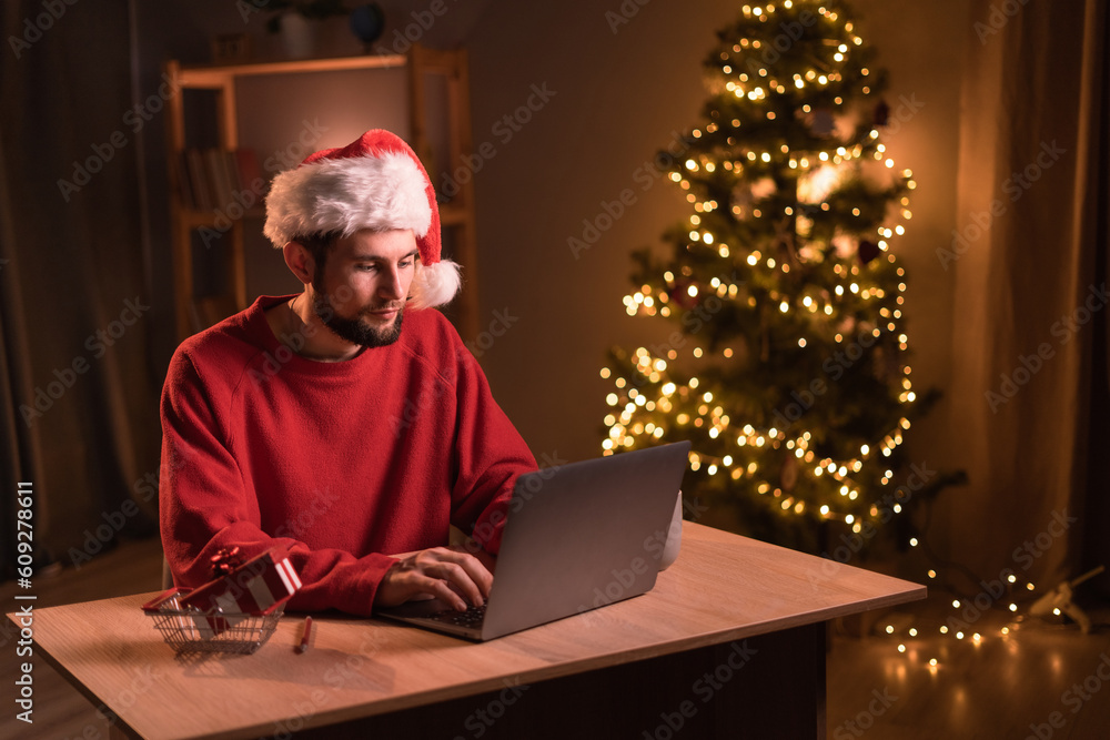 Smiling man sending e-mails or have shopping online on laptop on Christmas Eve at home. Smiling man sending e-mails or have shopping online on laptop on Christmas Eve at home.