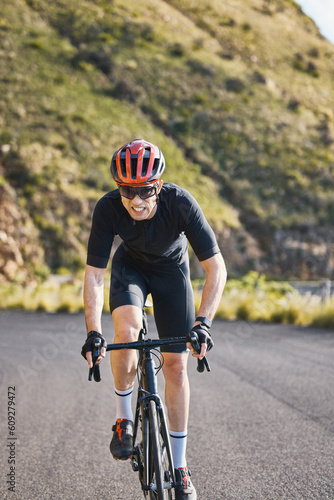 Fitness, bike and cycling with a sports man on a road through the mountain for cardio or endurance. Exercise, workout or training with a male cyclist riding his bicycle on an asphalt street in nature