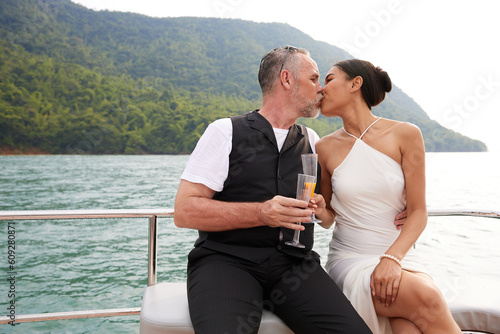 couple holding a glass and kissing in luxury yacht © offsuperphoto