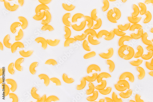 Scattered Uncooked Chifferi Rigati Pasta on White Background. Fat and Unhealthy Food. Classic Dry Macaroni Texture. Italian Culture and Cuisine. Raw Pasta