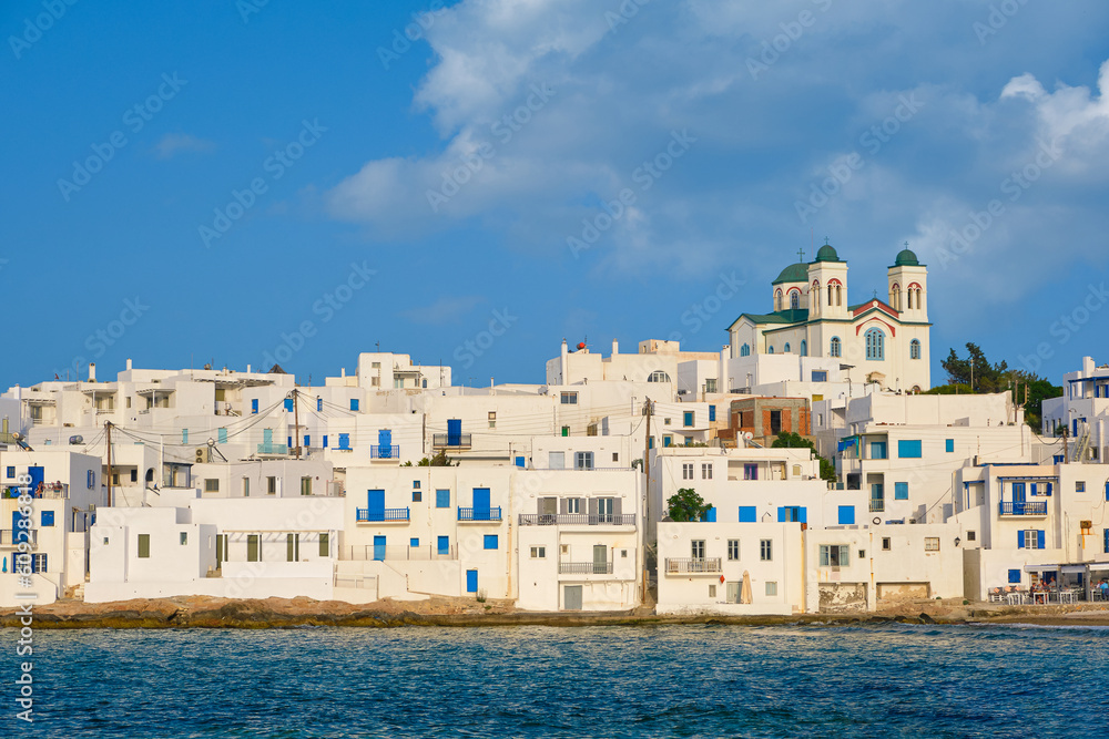 Greek whitewashed houses and church by seafront on sunny day, Naoussa