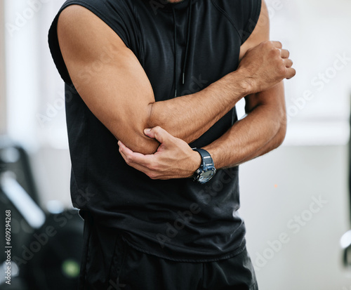 Fitness, gym and injury, man with elbow pain and medical emergency from workout at sports studio. Exercise, health and wellness, bodybuilder with hand on muscle ache while training and arm cramp. photo