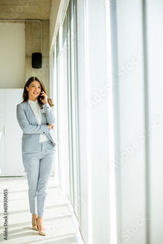 Free Download Young woman using mobile phone by the office window - GFXLoad