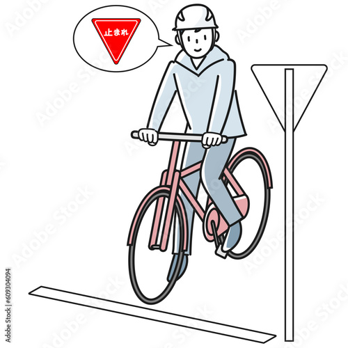 標識を見て一時停止する自転車に乗った若い男性