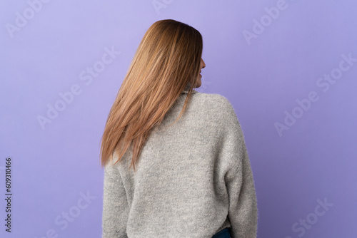 Young Slovak woman isolated on purple background in back position and looking side © luismolinero