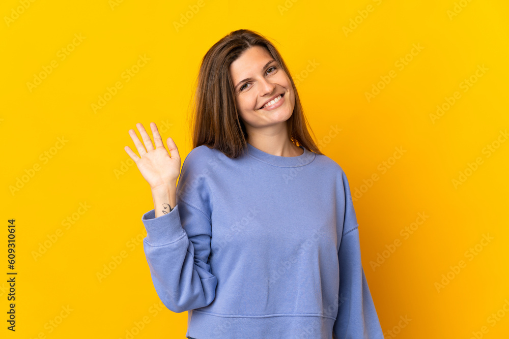 Young Slovak woman isolated on yellow background saluting with hand with happy expression Young Slovak woman isolated on yellow background saluting with hand with happy expression