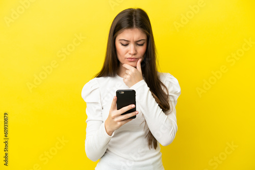 Young caucasian woman isolated on yellow background thinking and sending a message