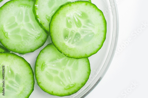 Thinly sliced slices of fresh green cucumber in a Petri dish.