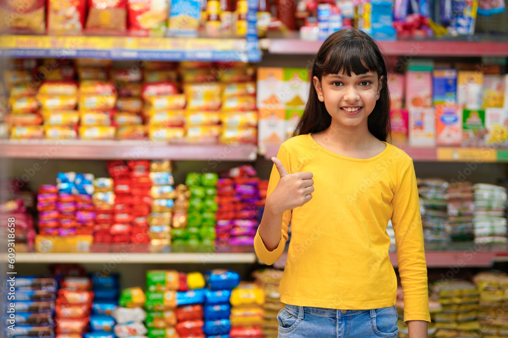 Indian girl showing thumps up at grocery store.