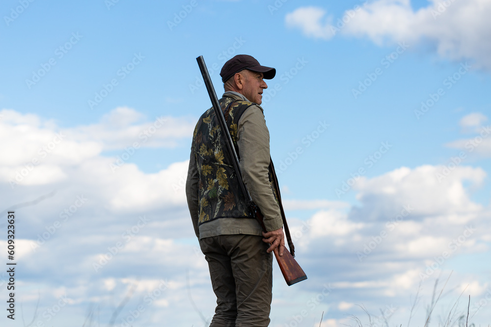 Mature man hunter with gun while walking on field. Mature man hunter with gun while walking on field.