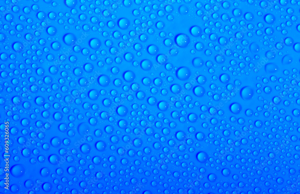 Water drops on glass as a background. Condensation on a cold drink. Blue background with drops texture.