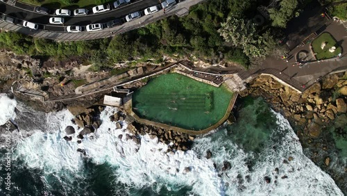 People swimming in Bronte Baths ocean pool with waves crashing.