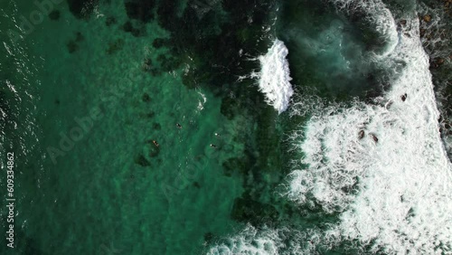 Surfers floating in ocean at Bronte with waves crashing against rocks from above