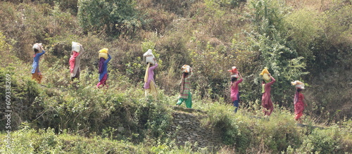 Some rural women carrying loads on their heads walking through mountain trails.